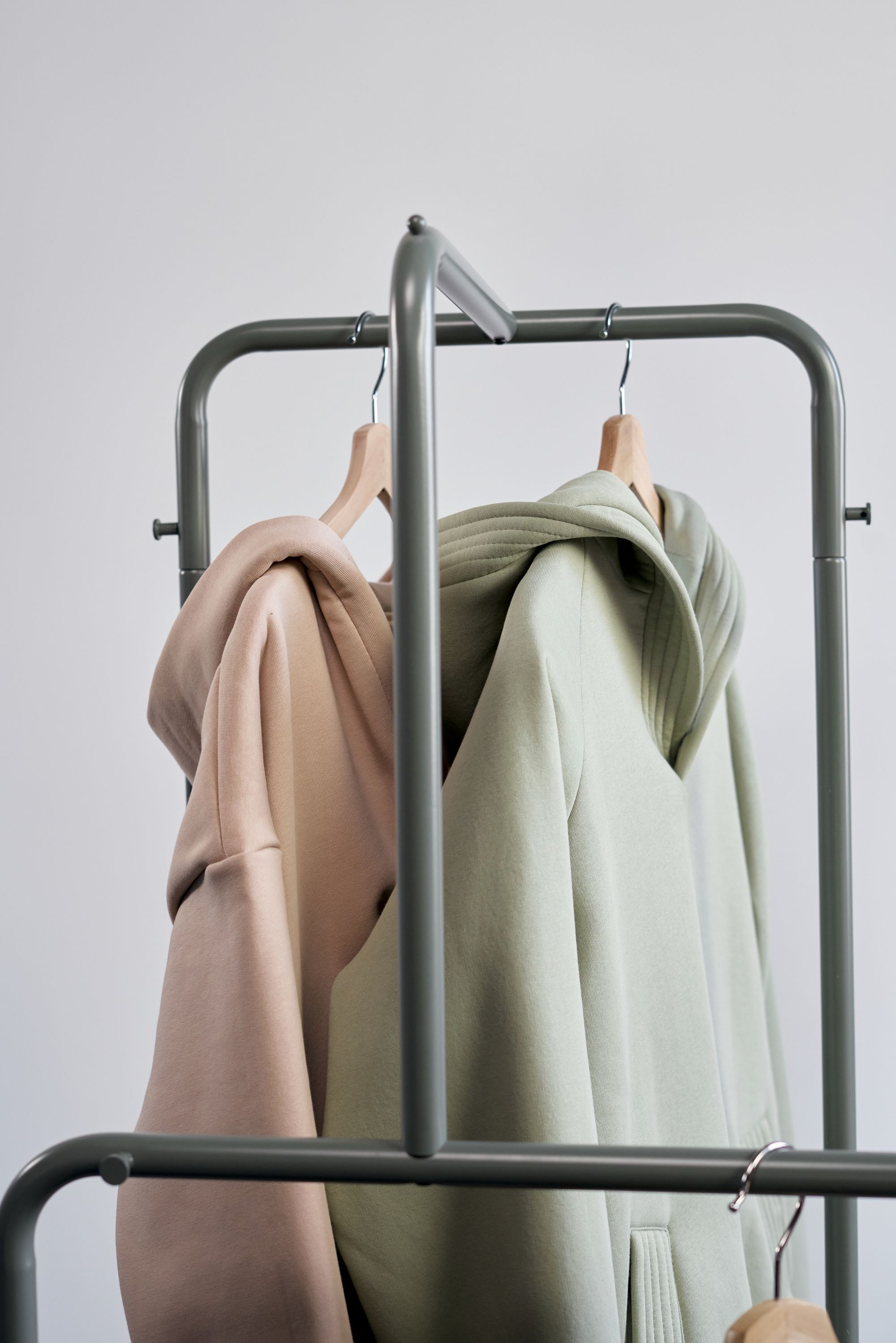 Beige and sage green hoodies hanging on a clothing rack